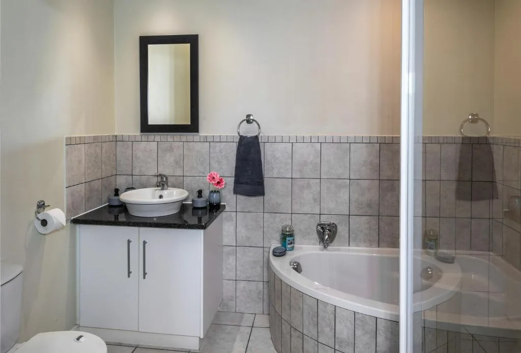 Modern bathroom with round sink, bathtub, and tiled walls