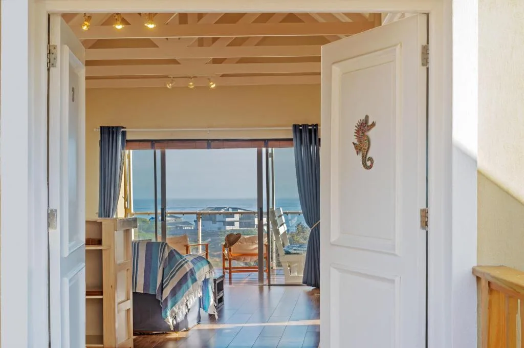 Bright bedroom with ocean view through glass doors and blue curtains