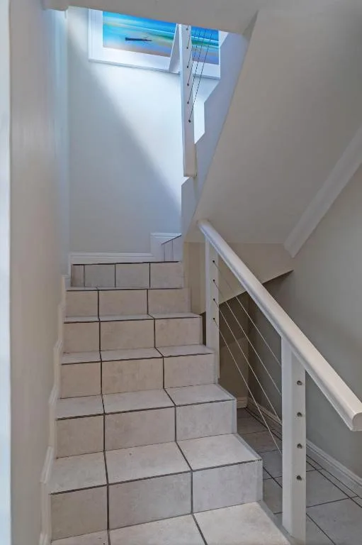 Modern staircase with tiled steps and metal railing, bright natural light