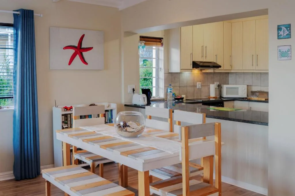 Open-plan dining area with wooden table and cream kitchen visible beyond