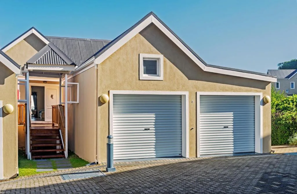 Modern cream-colored property with double garage doors and entrance portico