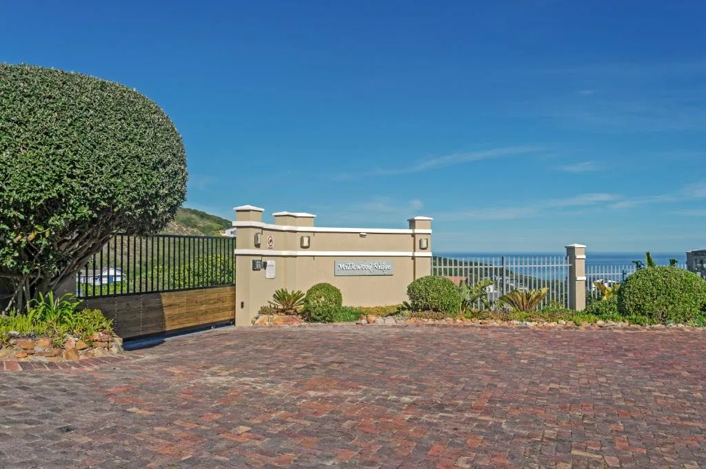 Cream-colored building entrance with manicured landscaping and ocean view beyond