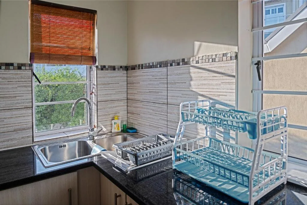Kitchen with stainless steel sink, dish racks, and window view