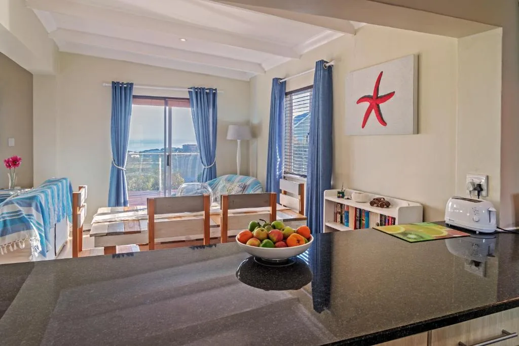 Open-plan lounge and dining area with ocean views through large windows and blue curtains