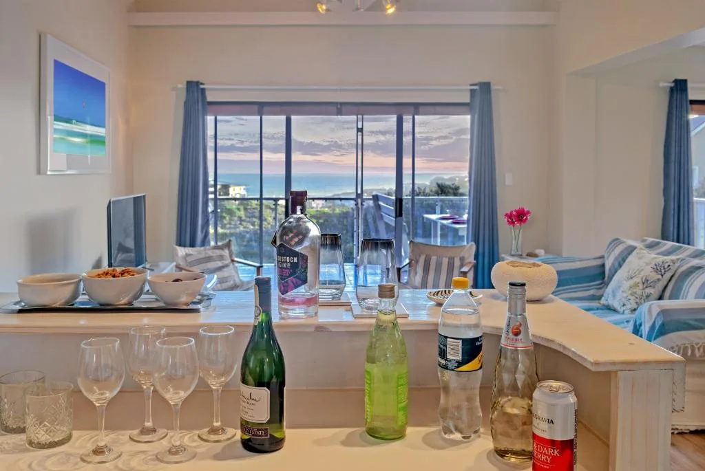 Open-plan lounge with ocean views through large windows and coastal scenery