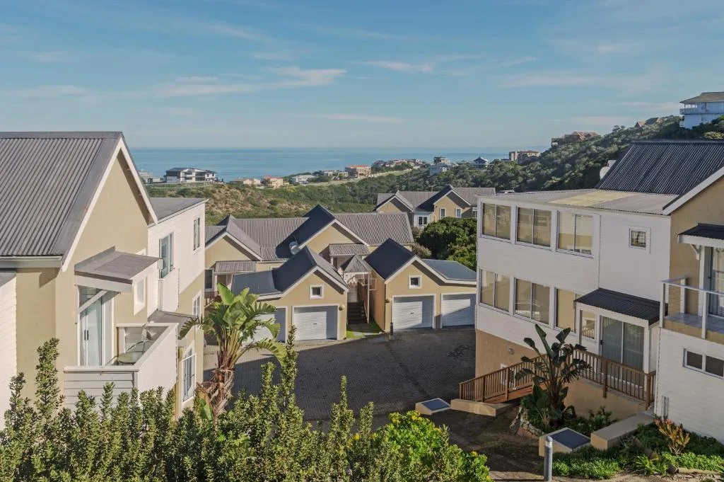 Ocean and coastline visible beyond residential properties on hillside