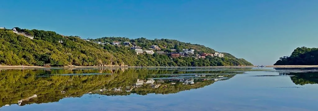Serene lagoon view with lush hillside homes and perfect water reflections
