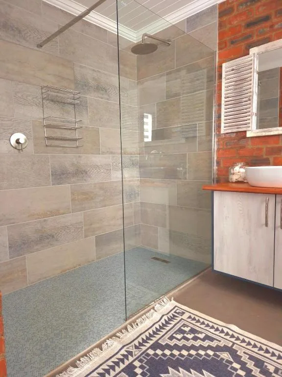Modern bathroom with walk-in shower, tiled walls, and white vanity sink