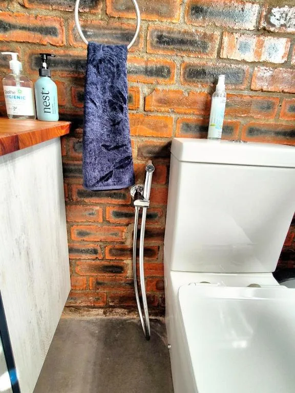 Bathroom with toilet, vanity, toiletries, and towel on brick wall