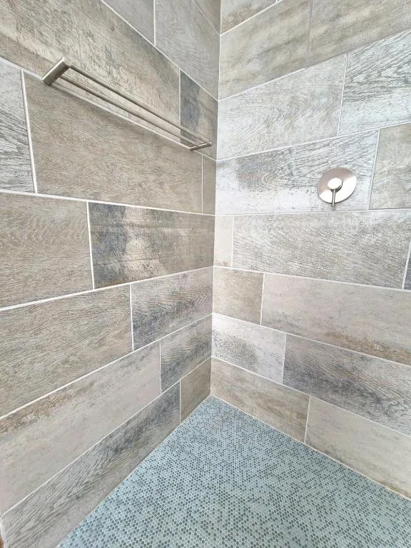 Modern shower stall with wood-grain tile walls and rainfall showerhead