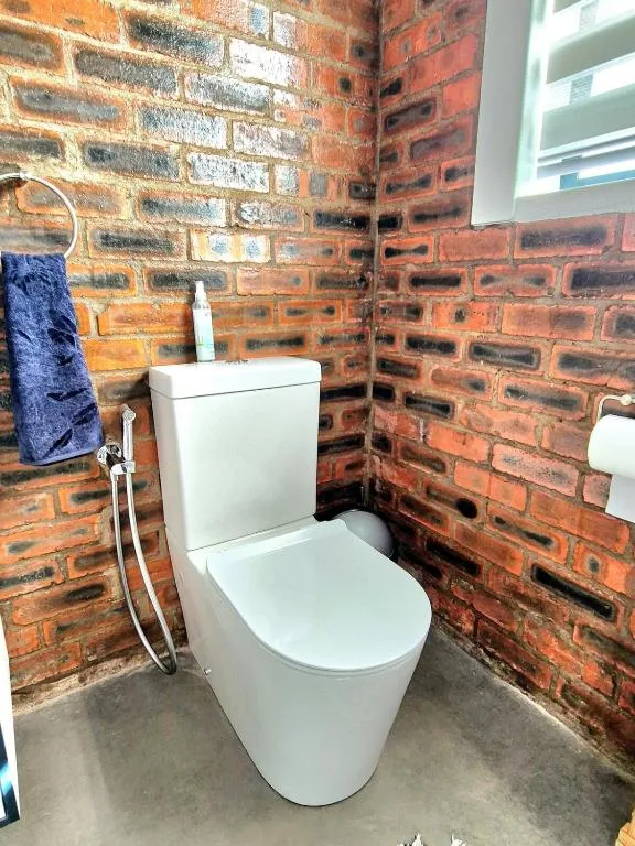 Modern white toilet against rustic exposed brick bathroom wall