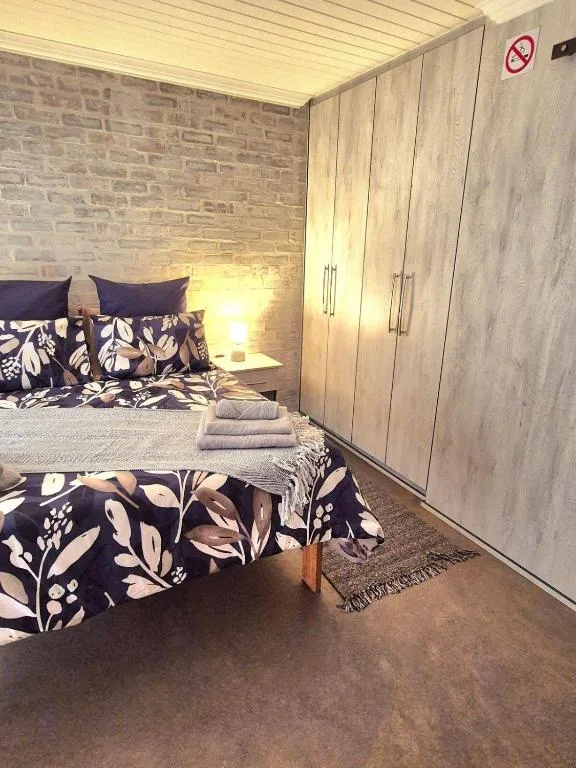 Cozy bedroom with patterned bedding, wooden wardrobes, and warm lighting