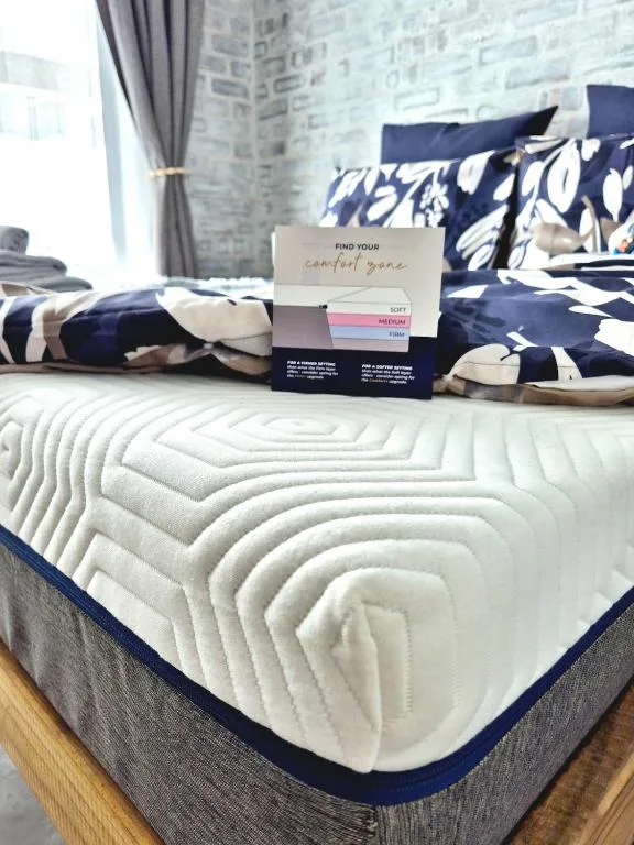 Bed with white quilted mattress, navy patterned pillows and bedding display