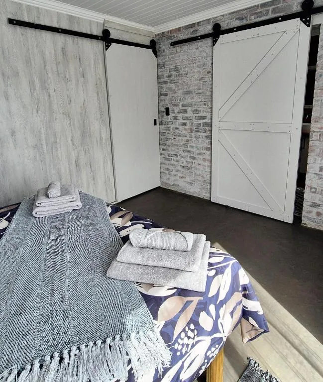 Modern bedroom with sliding barn doors and white rolled towels on bed