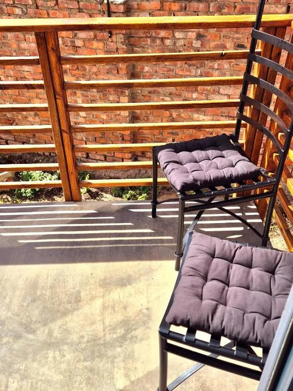 Outdoor patio with cushioned chairs and brick wall backdrop