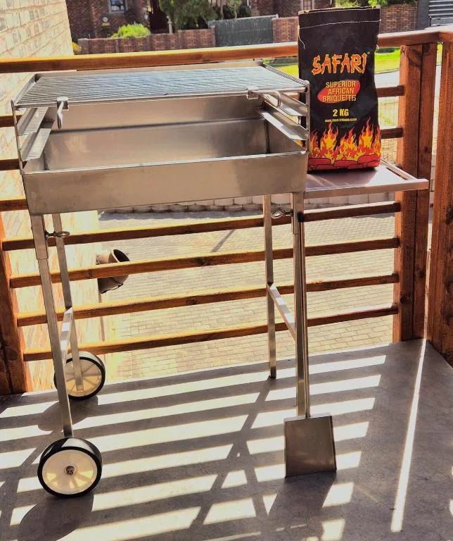 Stainless steel braai grill with charcoal on sunny deck area
