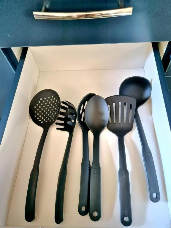 Black kitchen utensils organized neatly in white drawer compartment