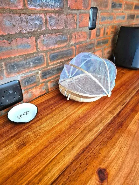 Food cover and coaster on wooden counter against exposed brick wall