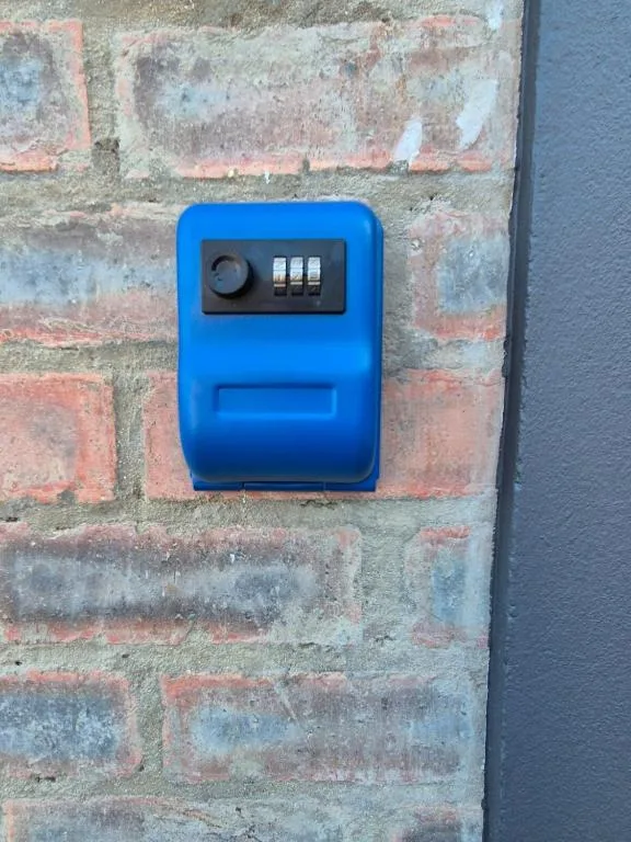 Blue combination lock key safe mounted on weathered brick wall
