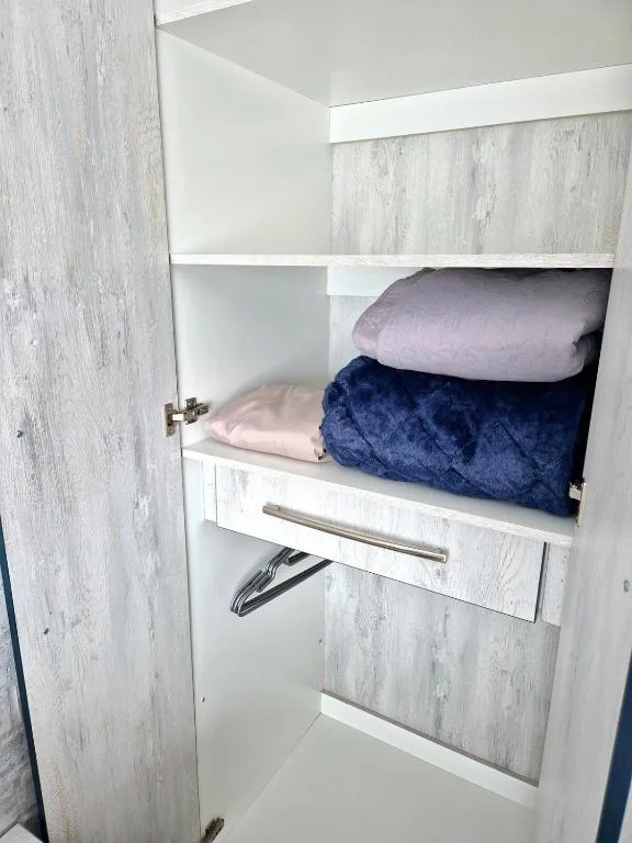 Built-in linen closet with folded towels and bedding neatly organized