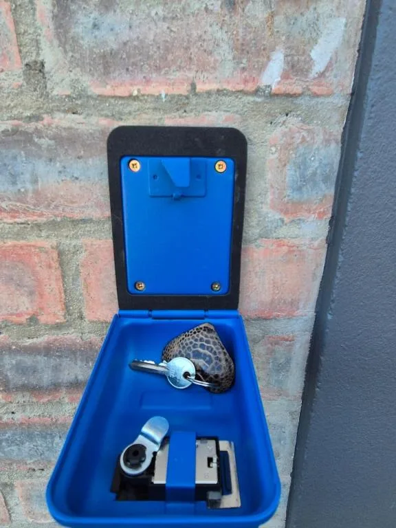 Blue key holder box mounted on brick wall with keys inside