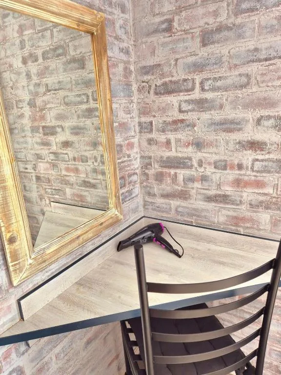 Bathroom vanity area with brick wall and gold-framed mirror