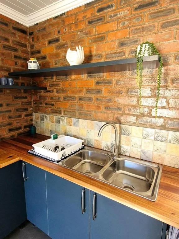 Modern kitchen with stainless steel sink, wooden counters, and brick walls