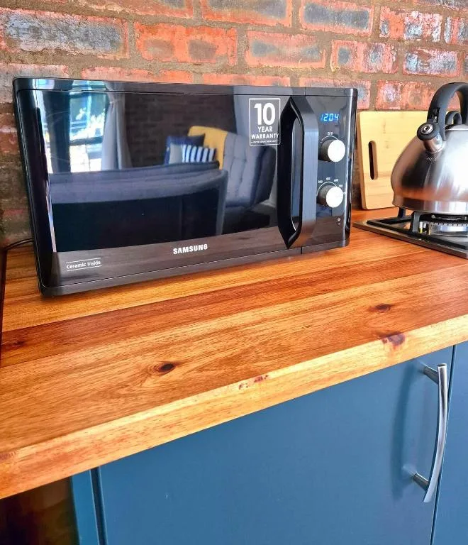 Modern black Samsung microwave on wooden kitchen counter with appliances