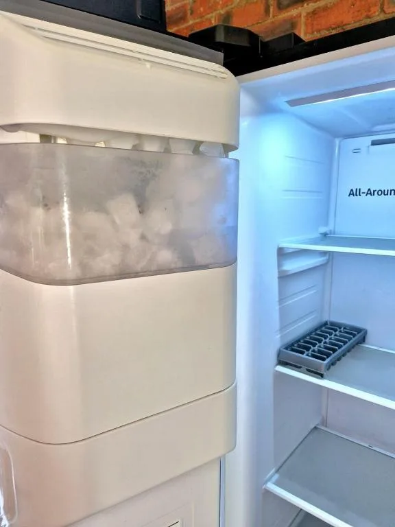 Open refrigerator displaying ice maker and empty shelves clearly