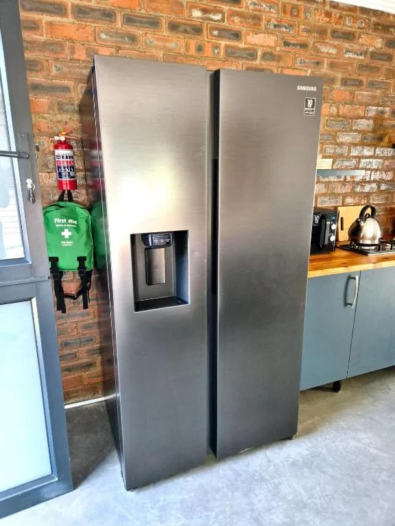 Modern stainless steel Samsung refrigerator in brick kitchen with first aid box