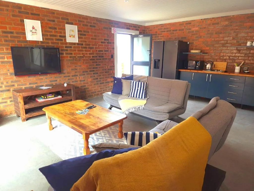 Open-plan lounge with comfortable seating, wooden coffee table, and wall-mounted television