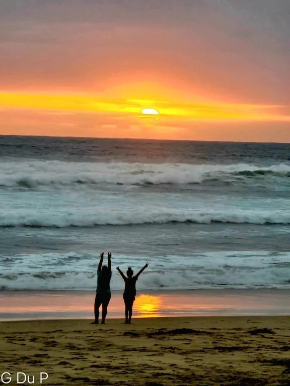 Golden sunset over ocean waves with silhouetted figures on beach
