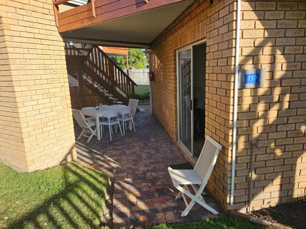 Covered brick patio with white dining furniture and lounge chair