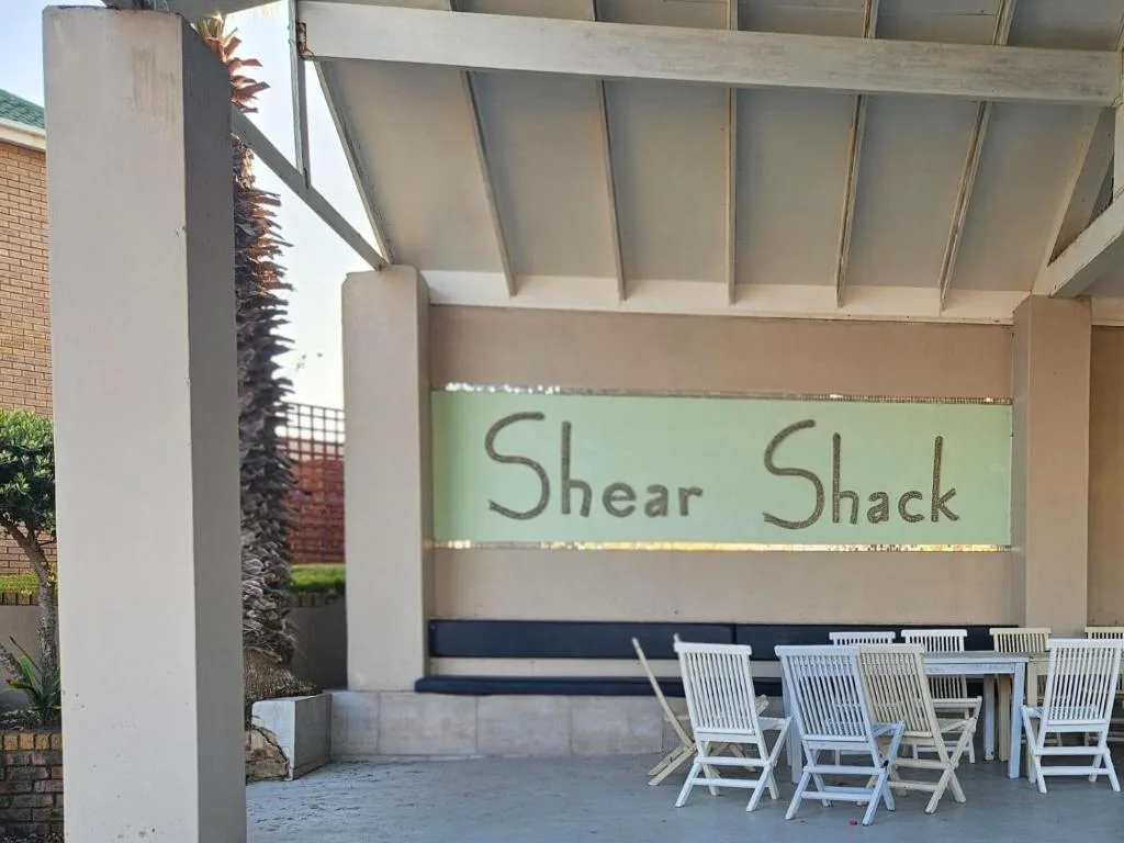 Covered outdoor seating area with white loungers under pergola