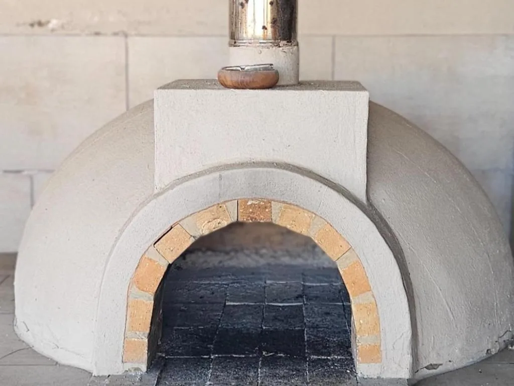 Traditional white-painted pizza oven with terracotta brick arch opening