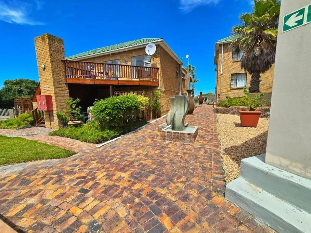 Brick building with wooden deck and palm trees, sunny day