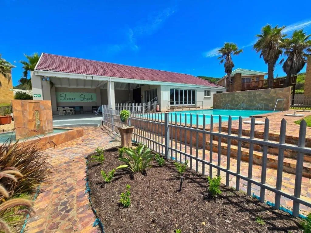 Turquoise swimming pool with white railing and beachfront property exterior