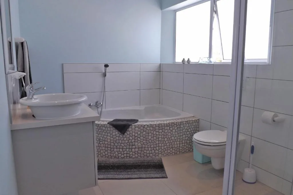 Modern bathroom with round sink, bathtub, and toilet fixtures