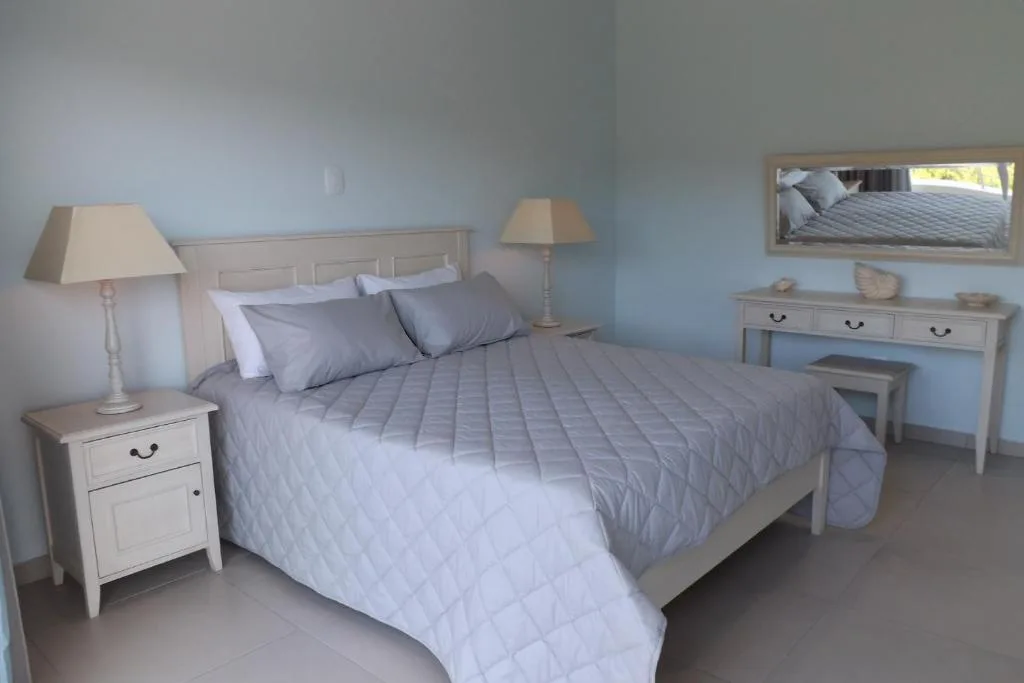 Bright bedroom with queen bed, white furniture, and soft blue walls