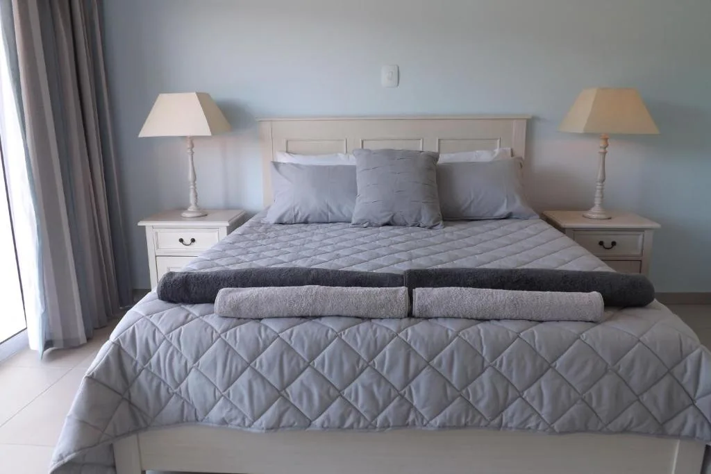 Spacious bedroom with queen bed, neutral bedding, twin bedside tables and lamps