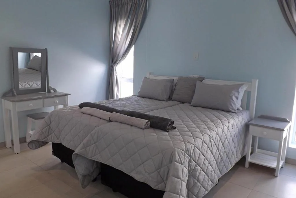 Bright bedroom with queen bed, gray bedding, and white furniture