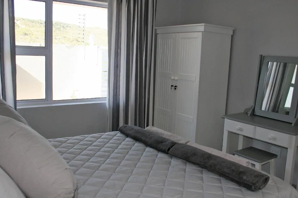 Bright bedroom with queen bed, white wardrobe, and mountain view through windows