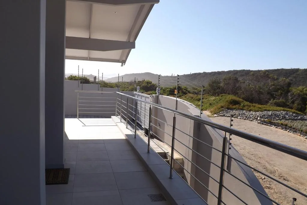 Modern outdoor deck with metal railing overlooking mountain landscape and vegetation