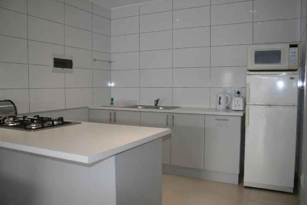 Modern kitchen with gas stove, white cabinetry, refrigerator, and island counter
