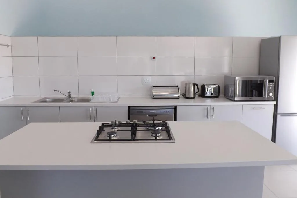 Modern white kitchen with gas cooktop, sink, appliances and ample counter space