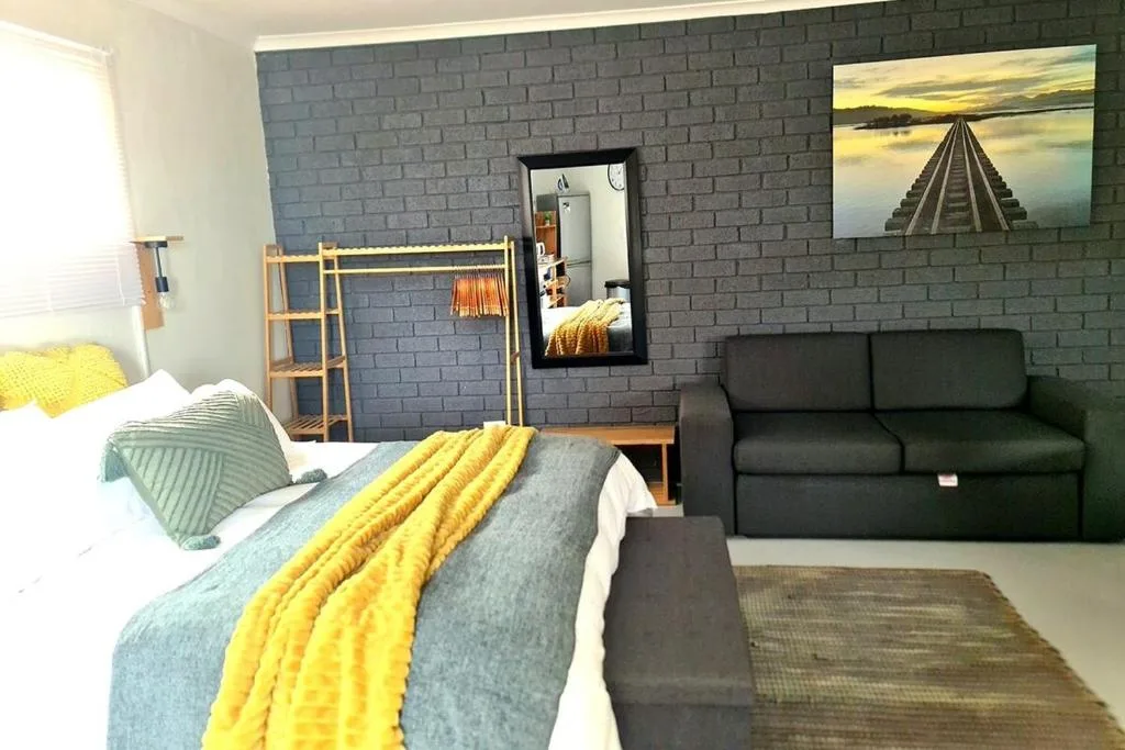 Studio bedroom with double bed, sofa, and brick accent wall