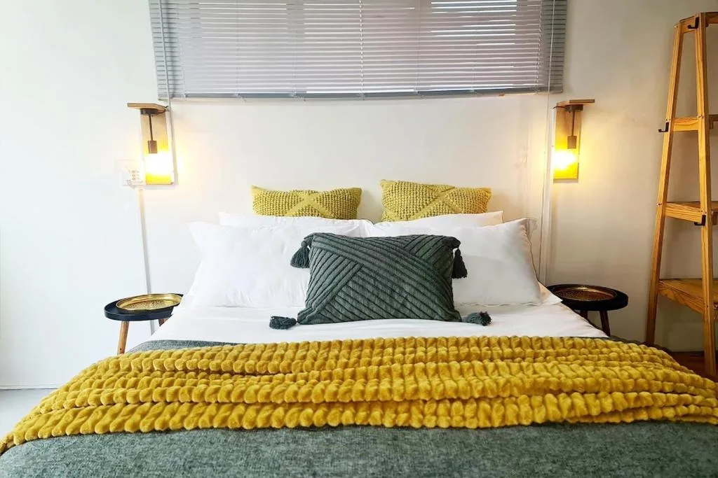 Modern bedroom with queen bed, yellow quilted throw, and pendant lighting