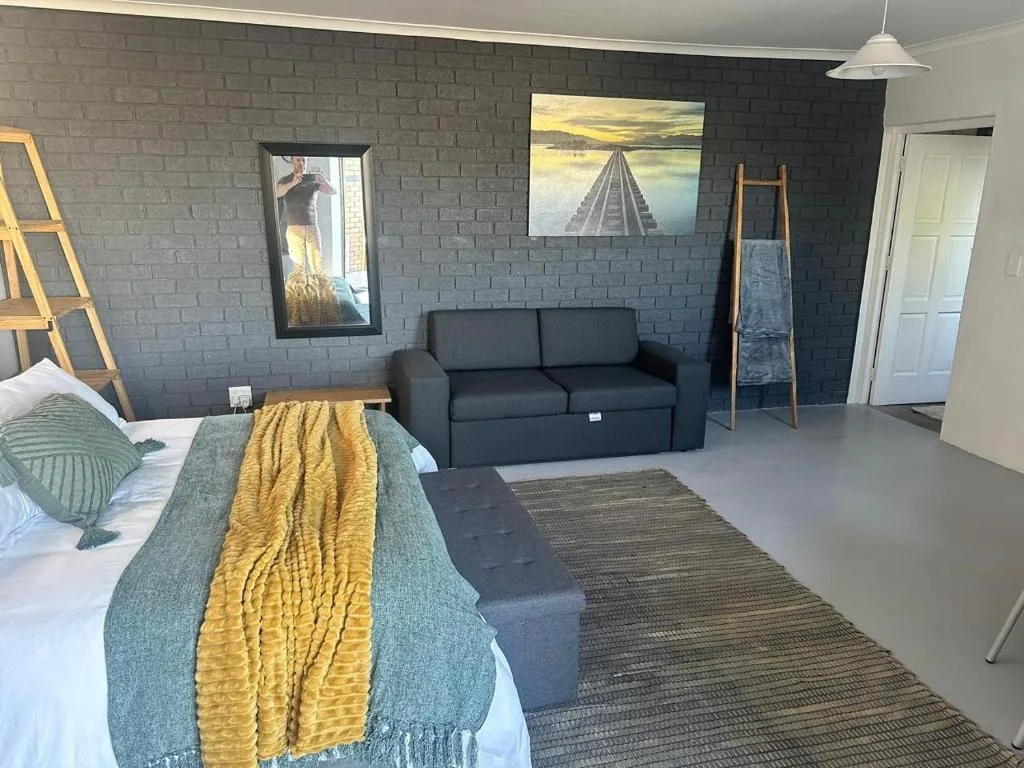 Spacious studio bedroom with sofa, black brick accent wall, and artwork