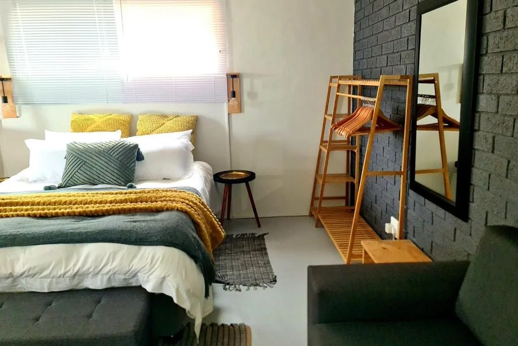 Bright bedroom with queen bed, yellow accents, and wooden bunk ladder