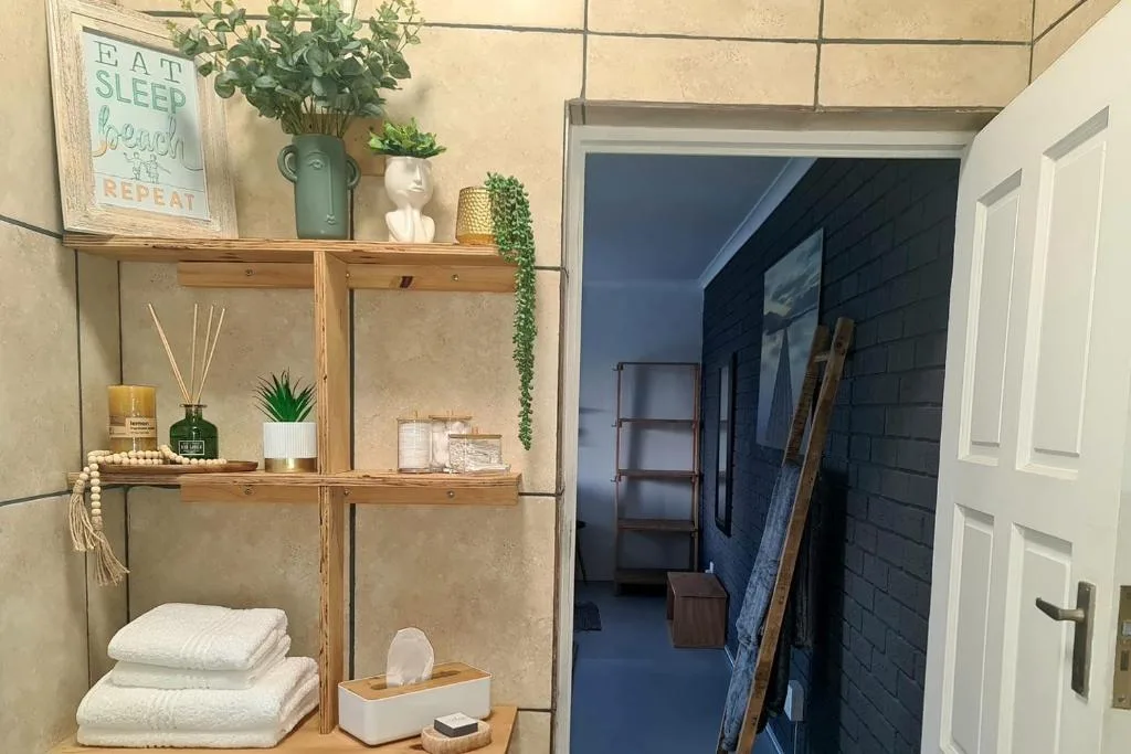 Wooden shelving unit with plants, towels, candles, and decorative items